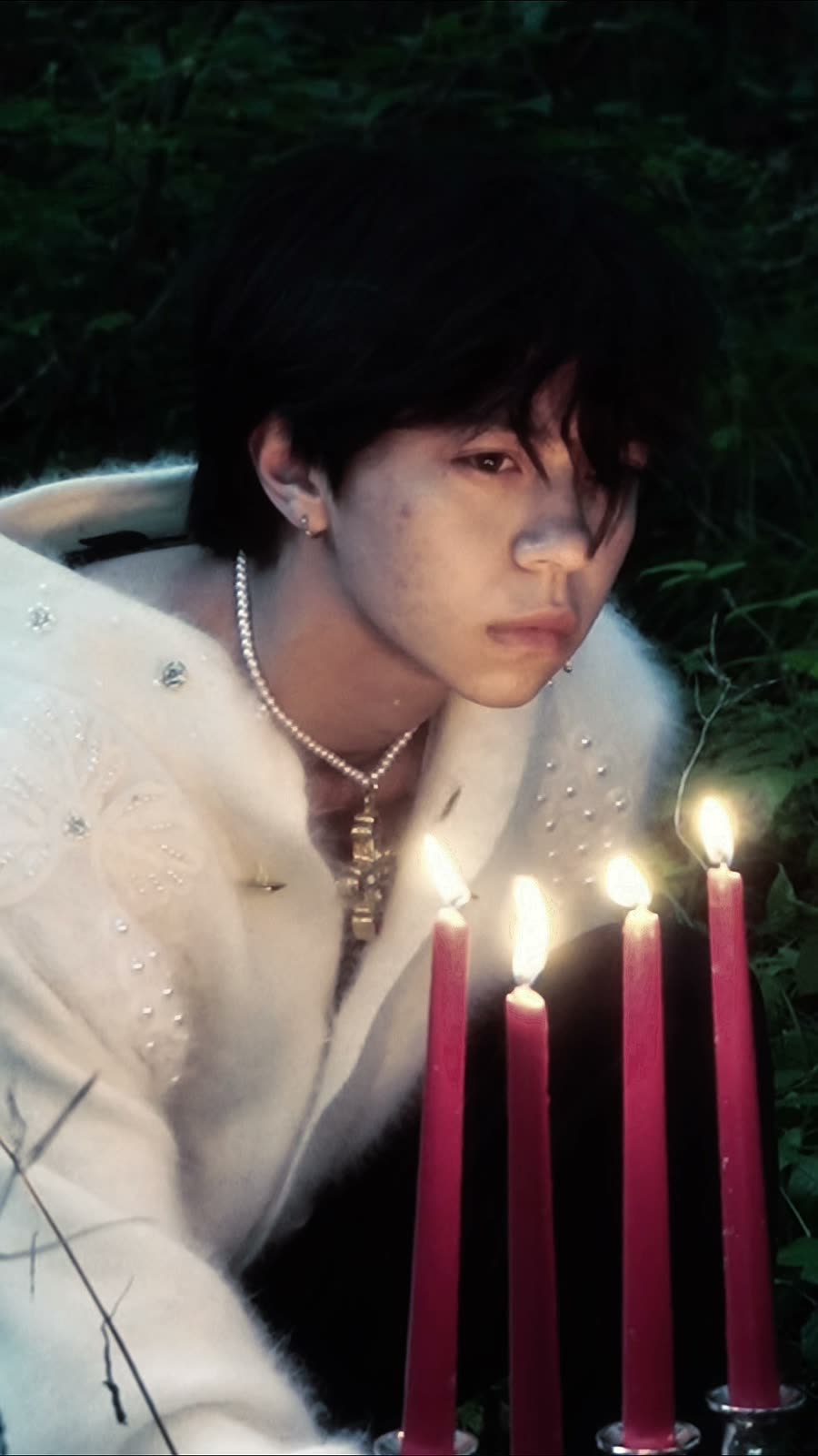 Jake Oscar H. photographed by candlelight in a forest at dusk